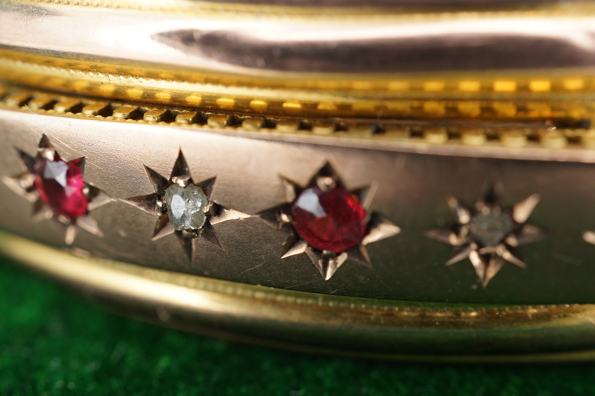 An Edwardian 9ct gold, and gypsy set ruby and diamond set hinged bangle, gross 11.4 grams, together with a gilt metal hinged bangle. Condition - poor.